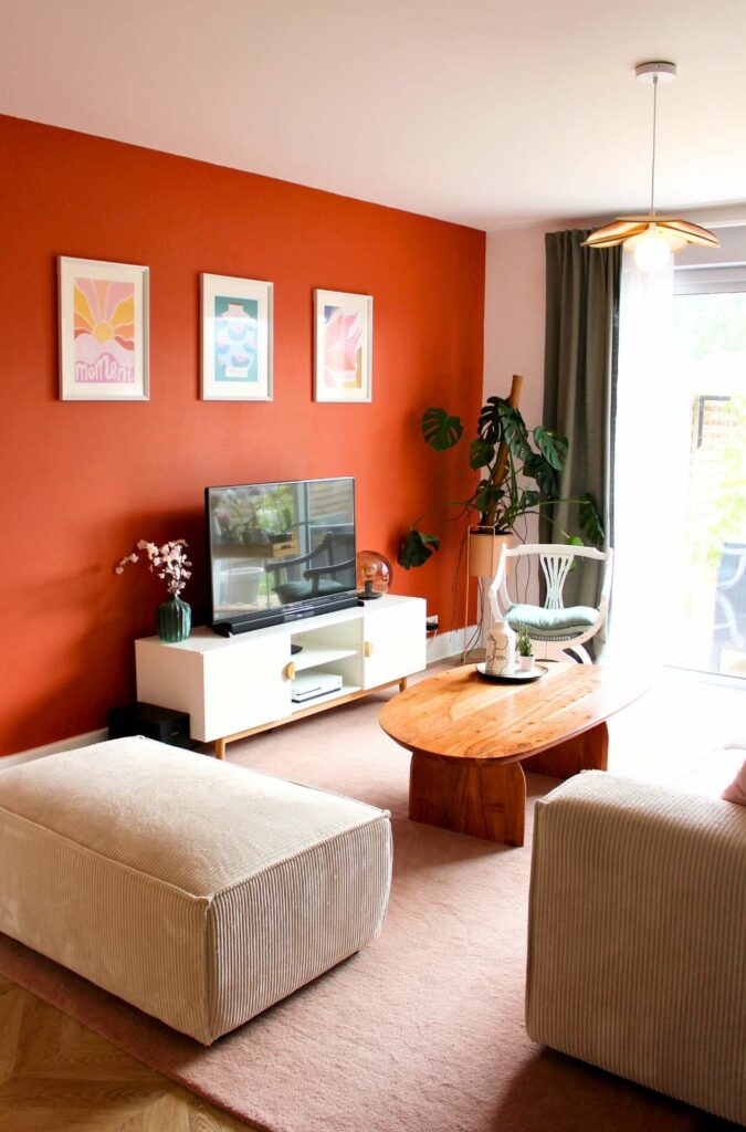 un salon convivial avec un mur terracotta, un canapé beige en velours et un tapis tout doux rose poudré
